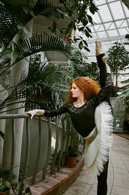 Free photo young female ballerina dancing in an indoors botanical garden