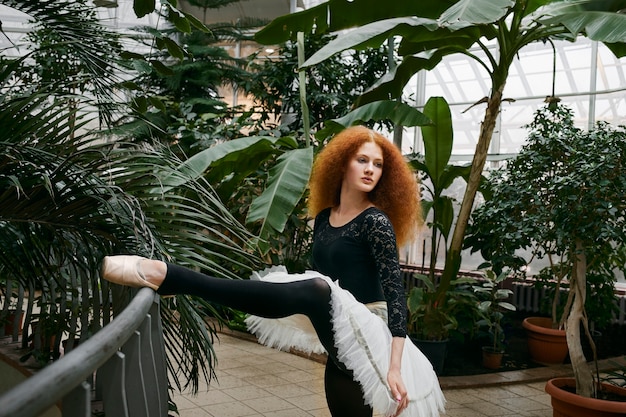 Free Photo young female ballerina dancing in an indoors botanical garden