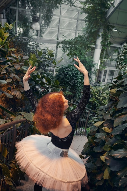 Free Photo young female ballerina performing in an indoors botanical garden