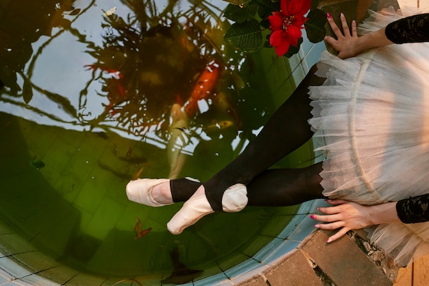 Free Photo young female ballerina resting near pool in an indoors botanical garden