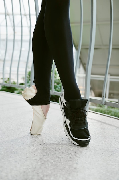 Free photo young female ballerina wearing pointe shoe and sneaker in an indoors botanical garden