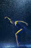 Free photo young female ballet dancer performing under water drops and spray. caucasian model dancing in neon lights. attractive woman. ballet and contemporary choreography concept.