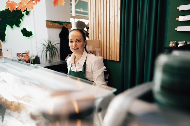 Free photo young female barista standing inside the coffee counter