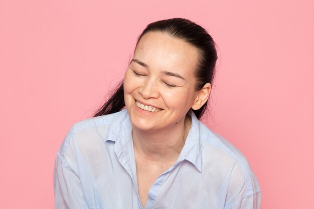 young female in blue shirt posing on the pink wall