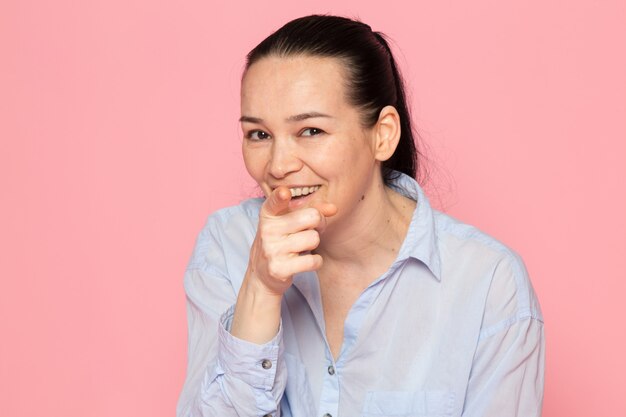 young female in blue shirt posing on the pink wall