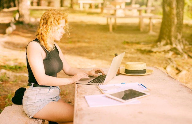 Free photo young female browsing internet on laptop in park