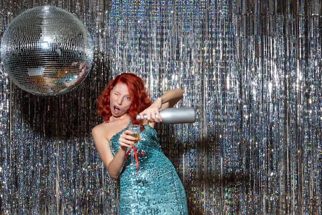 young female celebrating new year with champagne in party on shiny curtains