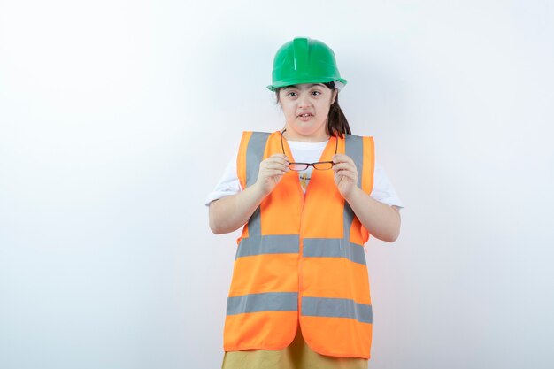 Young female construction worker wearing her glasses over white wall