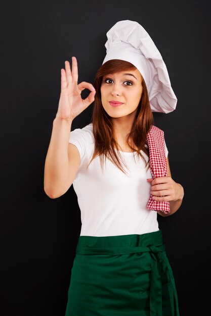 Young female cooking chef showing OK sign