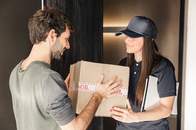 Free Photo young female courier delivering parcel to man at home