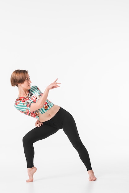 Young female dancer posing against white backdrop