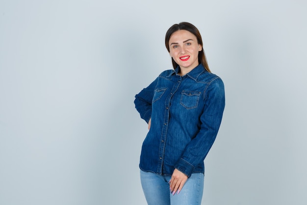 Free Photo young female in denim shirt and jeans holding hand on hip while posing and looking charming