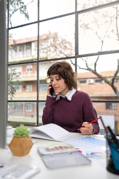 Young female designer talking on the phone