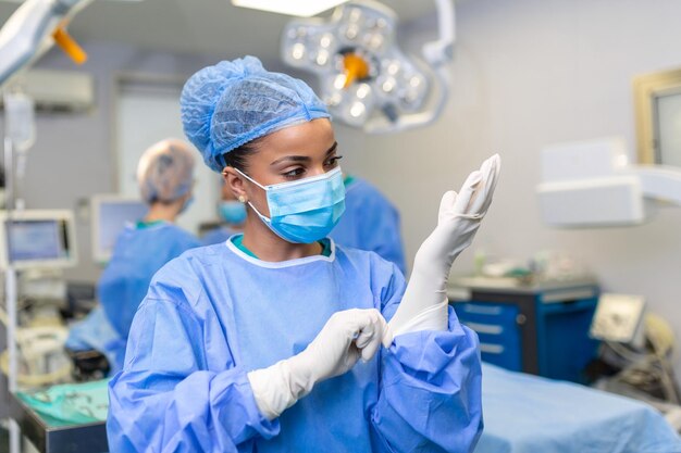 Young female doctor prepares for surgery wears blue surgical gloves in a coat and mask