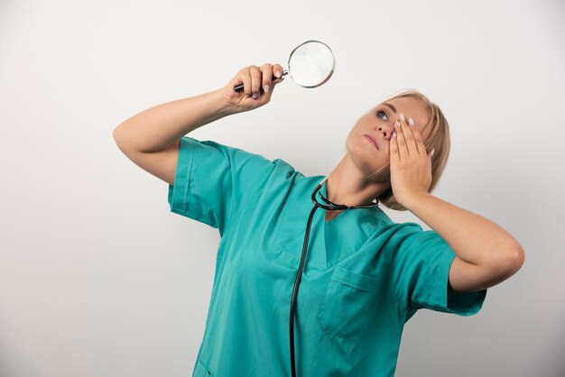 Young female doctor with stethoscope and magnifying glass .