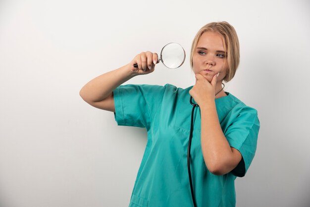 Young female doctor with stethoscope and magnifying glass .