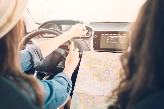 Young female driving car with map