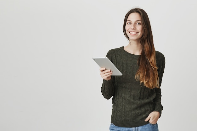 Young female employee, digital art freelancer using tablet, smiling