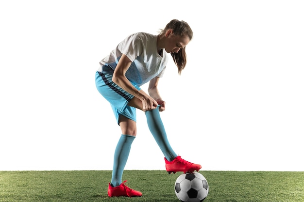 Free photo young female football or soccer player with long hair in sportwear and boots preparing for the game isolated on white background. concept of healthy lifestyle, professional sport, hobby.