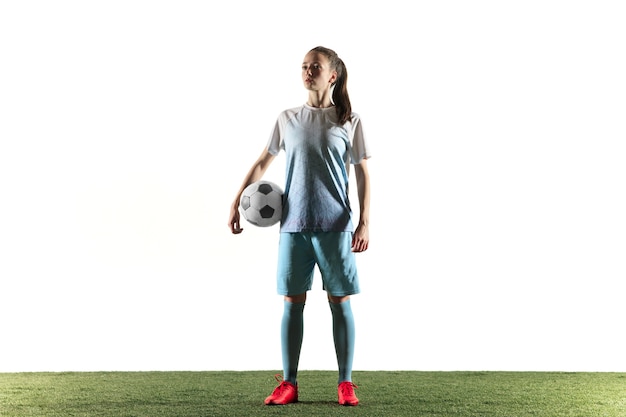 Free photo young female football or soccer player with long hair in sportwear and boots standing with the ball isolated on white background. concept of healthy lifestyle, professional sport, hobby.