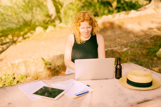 Free photo young female freelancing on laptop at desk in nature