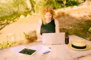 Free photo young female freelancing on laptop at desk in nature