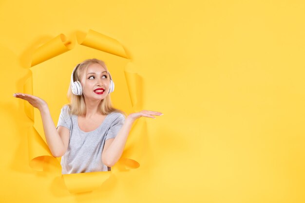 Young female in headphones on a yellow background sound ultrasound music audio