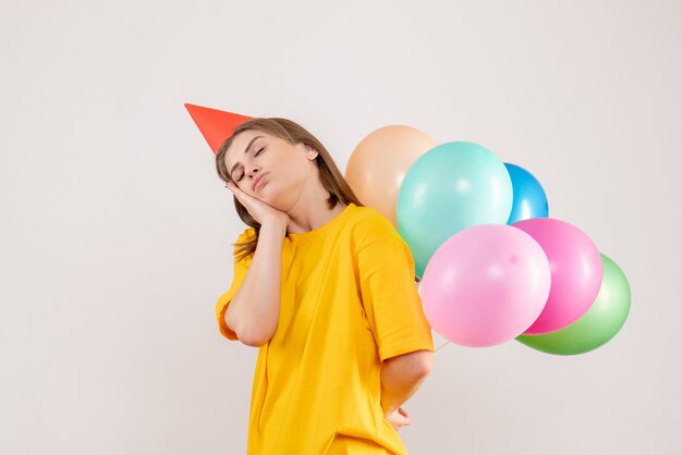 young female hiding colorful balloons behind her back on white