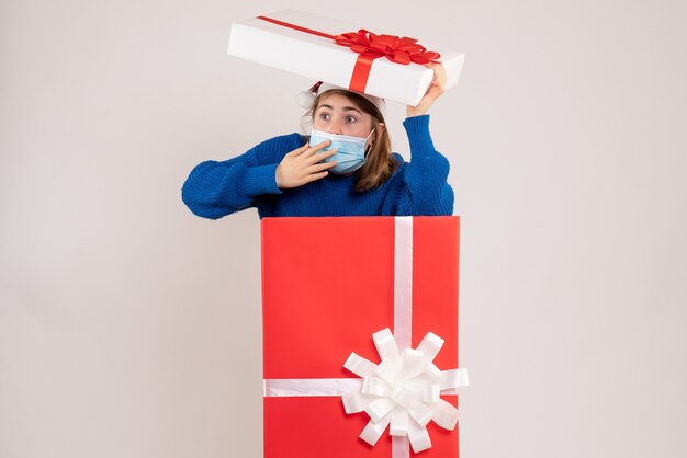 young female hiding herself inside present box on white