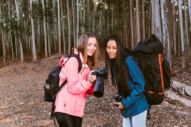 Young female hiker showing photograph on camera to her friend