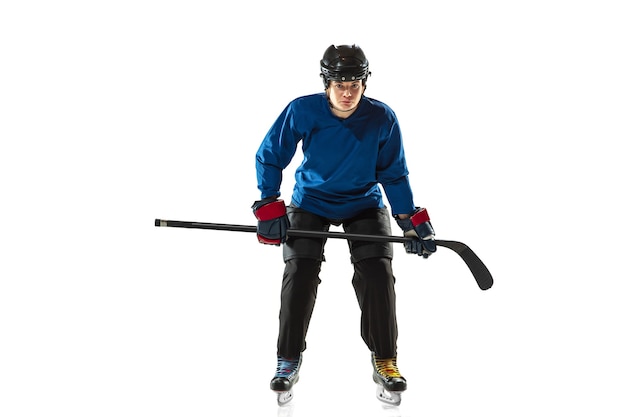 Young female hockey player with the stick on ice court and white background