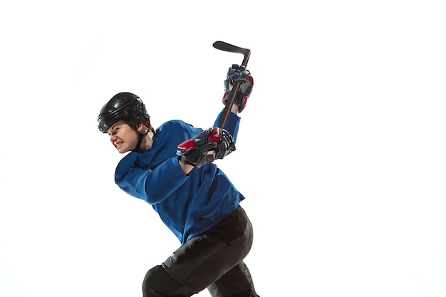 Free photo young female hockey player with the stick on ice court and white wall