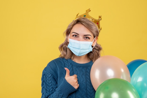 Free photo young female holding balloons in sterile mask on yellow