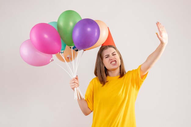 young female holding colorful balloons on white