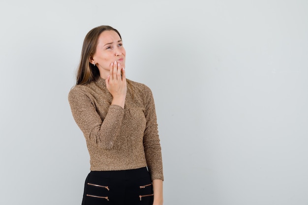 Free photo young female holding hand on her chin in blouse,skirt and looking painful , front view. space for text