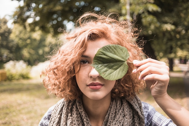 Free photo young female holding leaf near eye