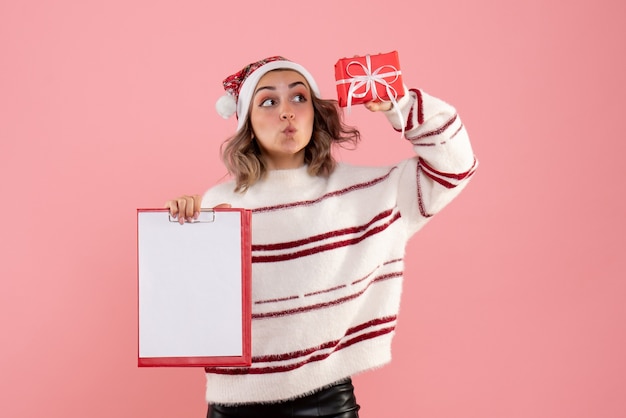 Free Photo young female holding little xmas present and note on pink