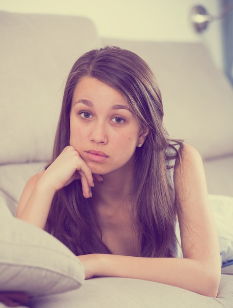 Young female is lying stressed and lonely on sofa