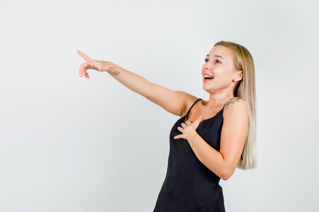 Young female laughing and pointing finger to side in black singlet and looking happy.