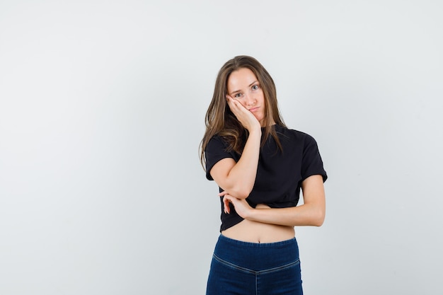 Free Photo young female leaning cheek on raised palm in black blouse, pants and looking hopeless