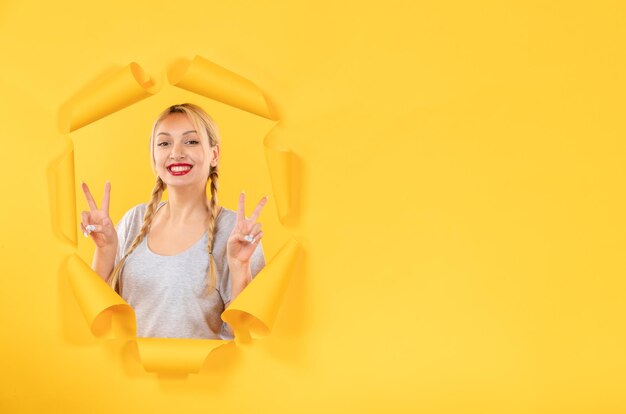 Young female looking from torn yellow paper background sale facial window indoor