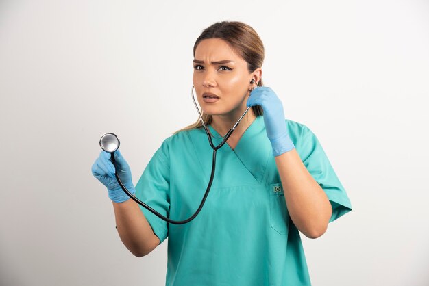 Young female nurse with stethoscope on white background