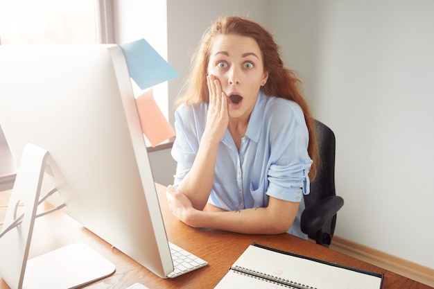 Young female office worker looking surprised and shocked