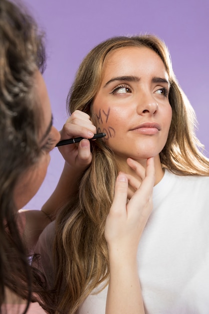 Free photo young female painting her friends face for protest