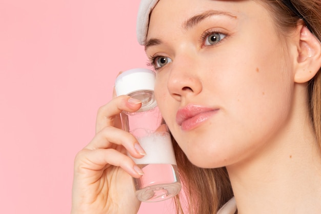 young female in pajamas and sleep mask holding spray on pink