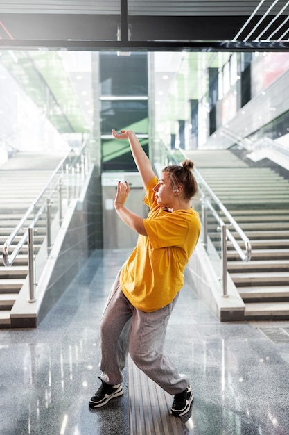 Free photo young female performer dancing next to stairs indoors