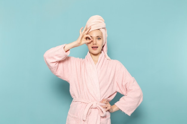 young female in pink bathrobe after shower cool posing on blue