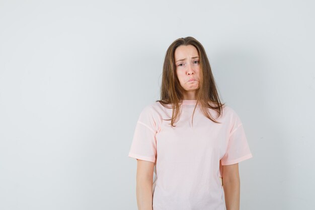 Young female in pink t-shirt and looking offended , front view.