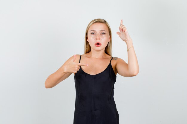 Young female pointing fingers with gun gesture in black singlet and looking serious 