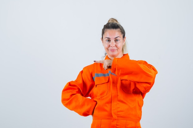 Young female pointing at right side in worker uniform front view.